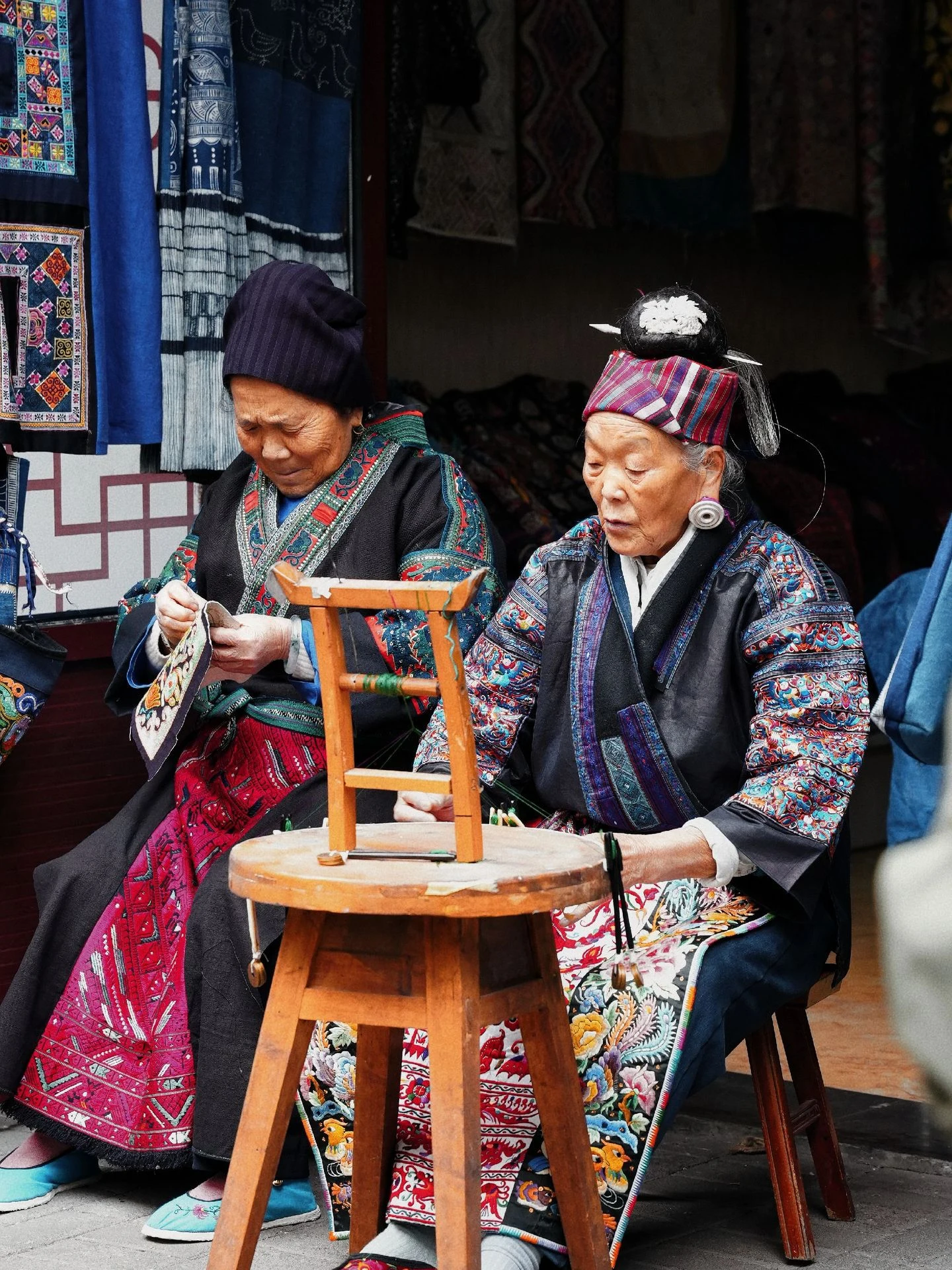 Elder Miao women working with traditional embroidered textiles