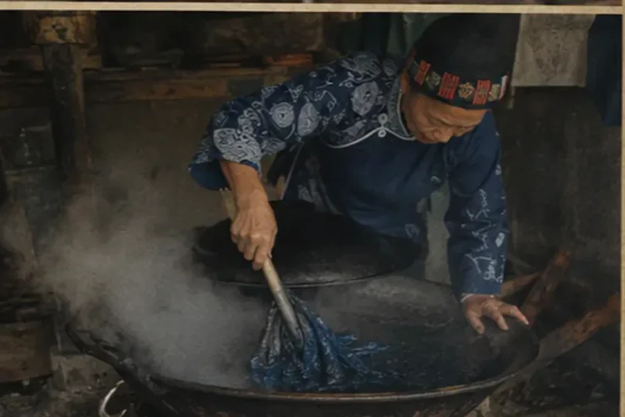 Artisan immersing real cloth during indigo dyeing